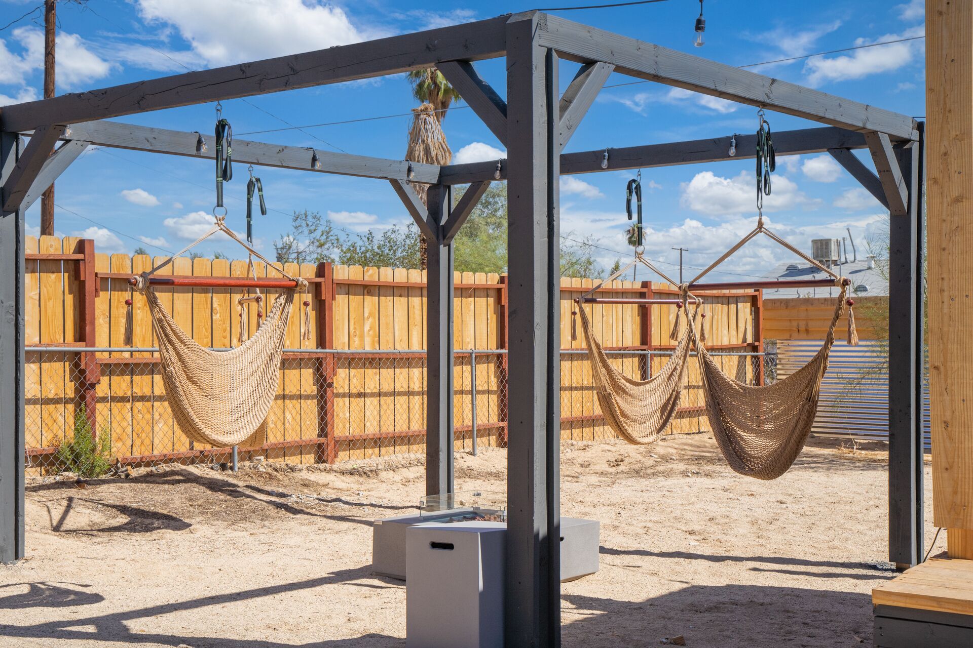 Una estructura de pérgola de madera con dos hamacas colgadas.