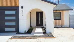 Ein modernes Haus mit weißer Fassade, einer dunkelgrauen Garagentür und einer schwarzen Haustür.