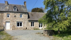 A stone house with a gravel driveway, a white door, and multiple windows.