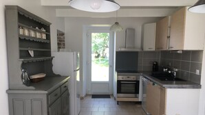 A kitchen with a built-in oven, a sink, and a dining area with a table and chairs.