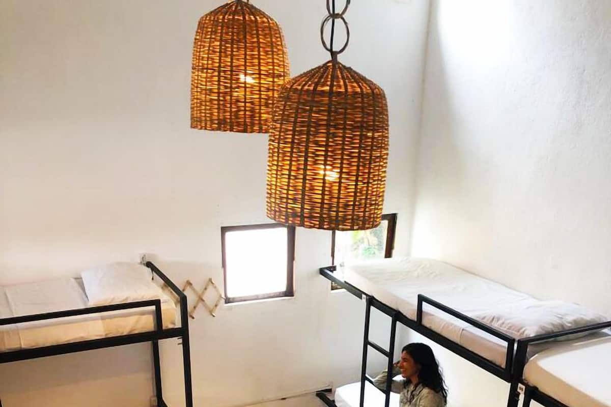 A bunk bed room with a hanging wicker light fixture and a window.