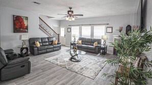 A modern living room with two sofas, a coffee table, a floor lamp, and a large plant. - Modern 5 Bedroom, 3 Full bathroom, + PlayStation. (Montgomery County)