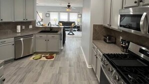 A modern kitchen with grey cabinets, stainless steel appliances, and a herringbone-patterned floor. - Modern 5 Bedroom, 3 Full bathroom, + PlayStation. (Montgomery County)