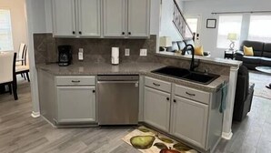 A modern kitchen with grey cabinets, a dishwasher, and a sink. - Modern 5 Bedroom, 3 Full bathroom, + PlayStation. (Montgomery County)