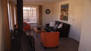 Una sala de estar con sofá, sillones, una mesita de centro y un ventanal con cortinas.