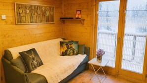 A cozy wooden cabin room with a sofa, a small table with a vase, and a painting on the wall. - Balcony overlooking the Mont-Blanc chain☀️parking (Les Houches)