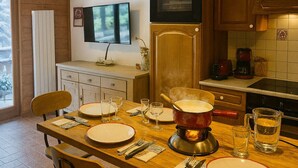A kitchen with a dining table set for four, a stove, oven, and a coffee maker. - Balcony overlooking the Mont-Blanc chain☀️parking (Les Houches)