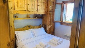 A wooden cabin-style bedroom with a bed, pillows, and towels. - Balcony overlooking the Mont-Blanc chain☀️parking (Les Houches)