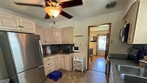 Una cocina equipada con refrigerador, estufa y ventilador de techo.