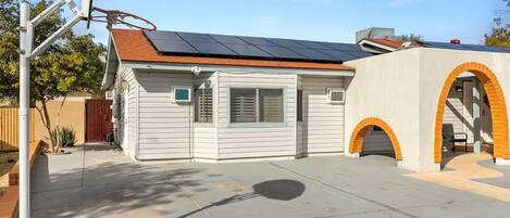 A single-story house with a solar panel roof, a garage with an archway, and a concrete driveway.