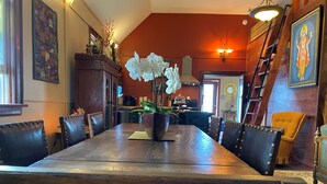 Un coin repas avec une table en bois, des chaises en cuir noir et une orchidée en pot.