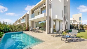A modern two-story house with a swimming pool, outdoor seating, and a well-maintained garden.