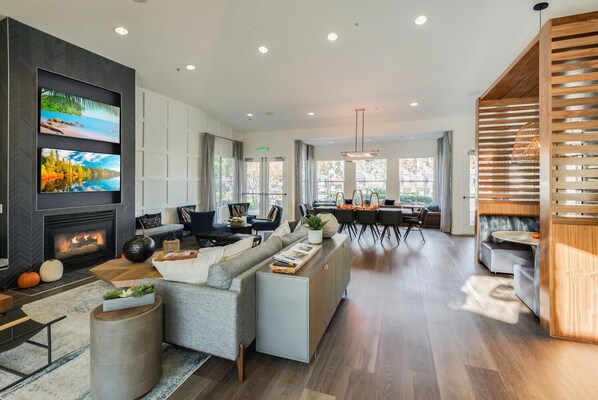 A modern living room with a fireplace, comfortable seating, a dining area, and large windows. - Lovely 1-bedroom Apartment In Great Location. (Roseville)