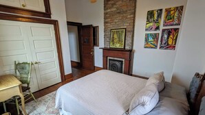 A bedroom with a bed, a chair, a fireplace, and artwork on the wall. - Half Okra Inn — Lovely, Historic, Streetcar in Sight, Restaurants & Bars Nearby (New Orleans)
