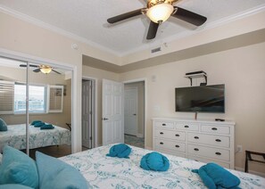 A bedroom with a bed, a ceiling fan, a TV, and a dresser. - Sanibel by ALBVR (Gulf Shores)