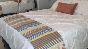 A hotel room with a large bed, a mirror, a painting on the wall, and a striped throw blanket. - Your Oasis Retreat: Pool, style, comfort, relaxation (Phoenix)
