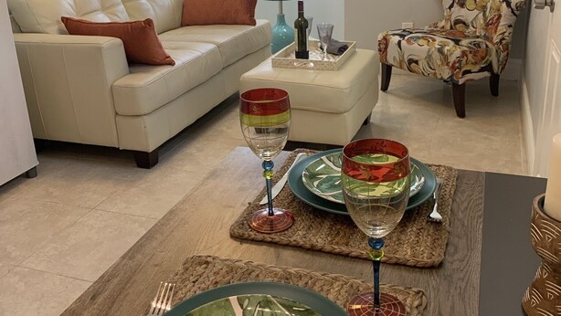 A living room with a sofa, a chair, a dining table set with plates and glasses, and framed artwork on the walls. - Your Oasis Retreat: Pool, style, comfort, relaxation (Phoenix)