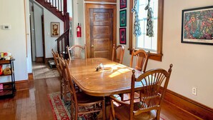 A dining area with a wooden table and chairs, a staircase, and a fire extinguisher on the wall. - Half Okra Inn — Lovely, Historic, Streetcar in Sight, Restaurants & Bars Nearby (New Orleans)