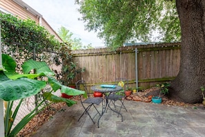 A patio with a round table and chairs, surrounded by potted plants and a wooden fence.