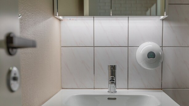 A bathroom with a white sink, a mirror, and a hand dryer.