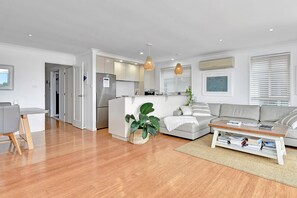 A modern living room with a grey sofa, a coffee table, and a dining area with a table and chairs.