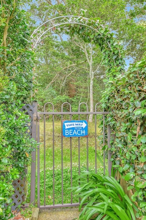 A metal gate with a sign indicating the direction to the beach.