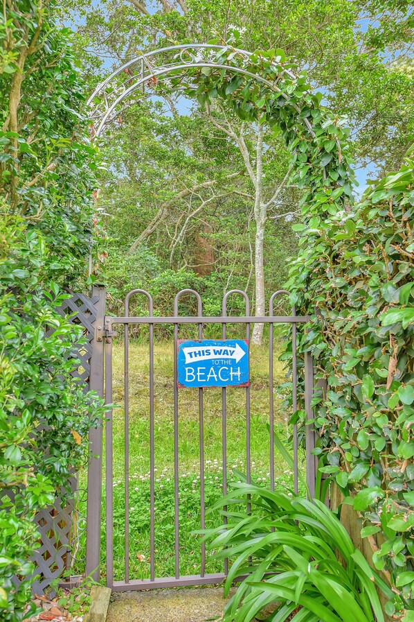 A metal gate with a sign indicating the direction to the beach.
