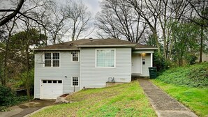 A single-story house with a front porch, a garage, and a small front yard.