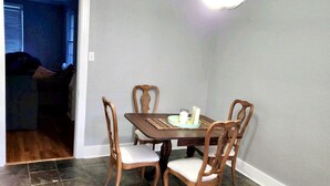 A dining area with a wooden table and chairs, a ceiling light, and a tiled floor.