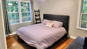 A bedroom with a bed, a ceiling fan, and a window with curtains.