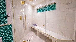 Un baño moderno con ducha acristalada, un banco y un lavabo con espejo.