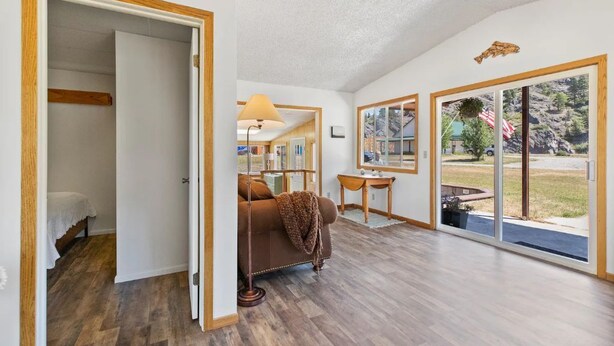 A spacious living area with a large sliding glass door leading to a backyard, a cozy seating area with a sofa, and a dining table. - Montana Missouri River Fly Fishing Lodge -3BR & 2 bath, Sleeps 8 (Cascade)