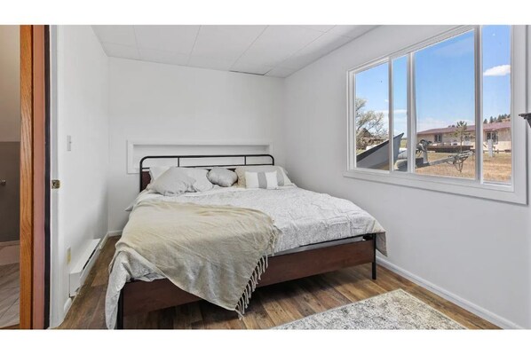 A bedroom with a bed, a window, and a view of the outside.