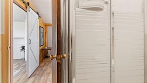 A hallway with a sliding door leading to a room with a white door and a towel hanging on the wall. - Montana Missouri River Fly Fishing Lodge -3BR & 2 bath, Sleeps 8 (Cascade)