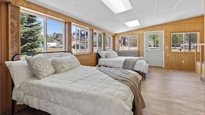 A room with two beds, large windows, wooden walls, and a door. - Montana Missouri River Fly Fishing Lodge -3BR & 2 bath, Sleeps 8 (Cascade)