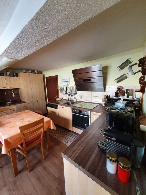 Cozinha moderna com armários de madeira, forno embutido, pia e área de jantar com mesa e cadeiras.