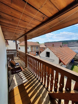 Varanda de madeira com vista para casas vizinhas e um céu limpo.