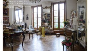 Una habitación amplia con un gran ventanal, un candelabro y una estatua.