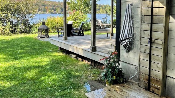 A wooden deck with outdoor seating and a view of a lake. - Lakeside Chalet, Sauna, Mont Orford & Village (Eastman)
