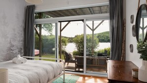 A bedroom with a large sliding glass door leading to an outdoor deck. - Lakeside Chalet, Sauna, Mont Orford & Village (Eastman)