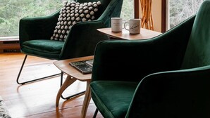 Una habitación moderna con dos sillones de terciopelo verde, una mesa de centro de madera y una lámpara de pie.