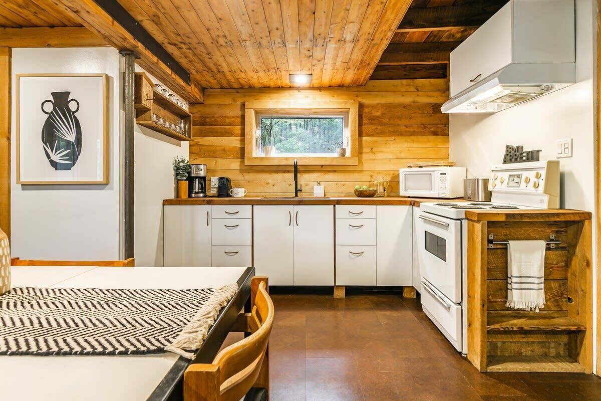 Un intérieur en bois comprenant un coin cuisine équipé d’un four à micro-ondes, d’une cuisinière et de placards.