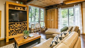 A cozy living room with a wooden ceiling, a television, a sofa, a coffee table, and a fireplace.