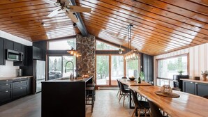 A modern kitchen with a central island, dark cabinetry, and large windows. - Le Cozy-St-Côme: Private Lake, Spa & Nature at Val St-Côme (Saint-Côme)