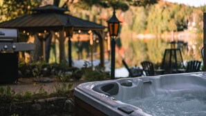 A hot tub in a serene outdoor setting with a gazebo and string lights in the background. - Le Cozy-St-Côme: Private Lake, Spa & Nature at Val St-Côme (Saint-Côme)