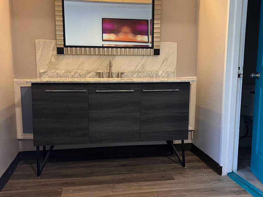 A modern bathroom with a marble vanity, a large mirror, and a built-in light fixture.