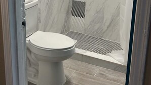 Een badkamer met douche, toilet en handdoekhouder.
