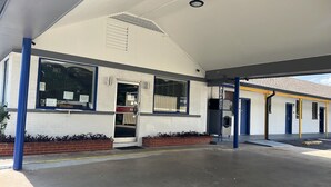 Een motel met een laag gebouw, een overdekte parkeerplaats en een kleine ingang met een deur.