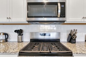 A kitchen with a stainless steel microwave above a stove, a coffee maker, and a utensil holder. - 5-bedroom townhome with a screened plunge pool at Solterra Resort, near Disney (Davenport)