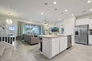 Una cocina moderna con una isla central, electrodomésticos de acero inoxidable y un comedor con sofá y mesa.